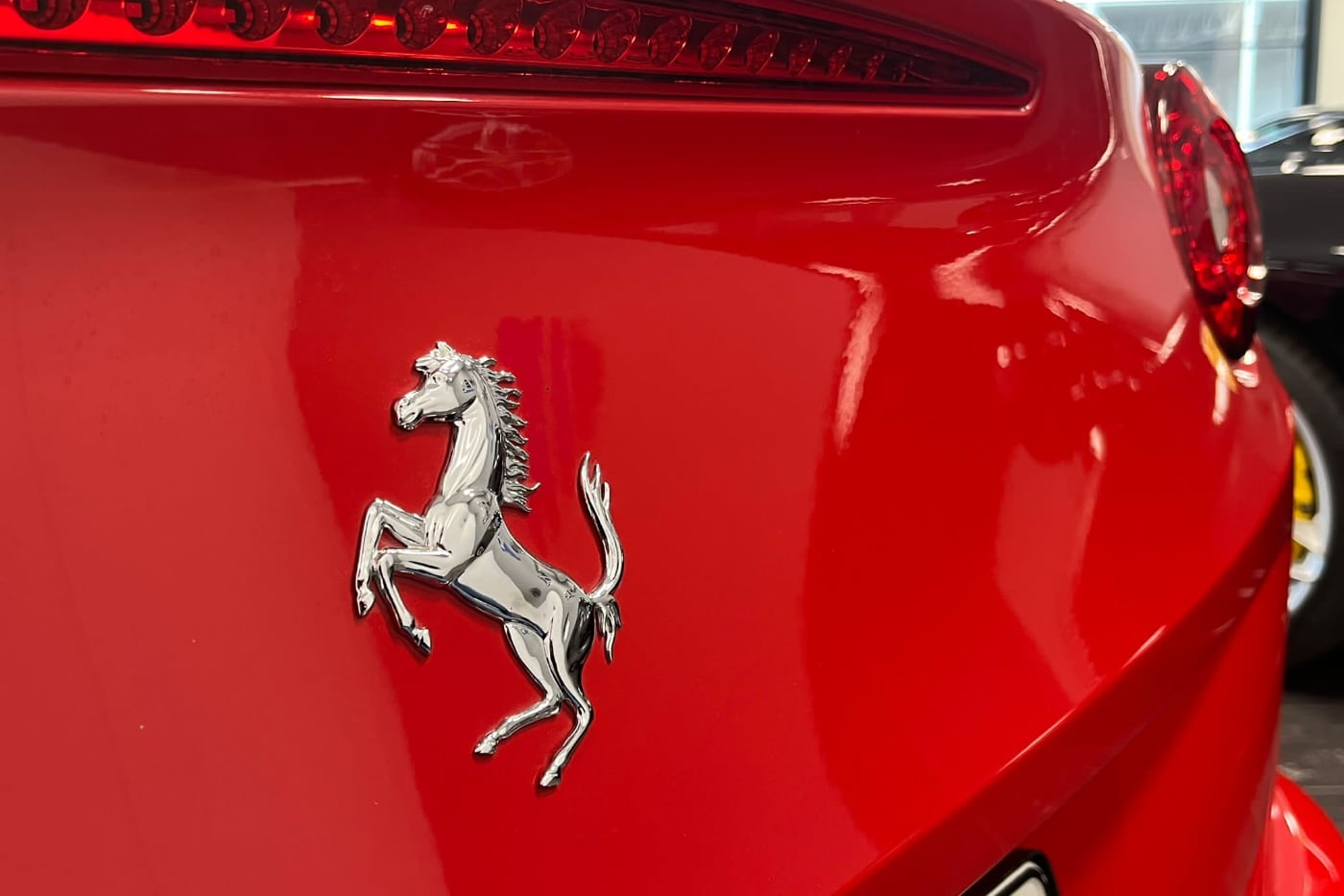 Närbild på en Ferrari som står parkerad i bilhallen och väntar på en kund